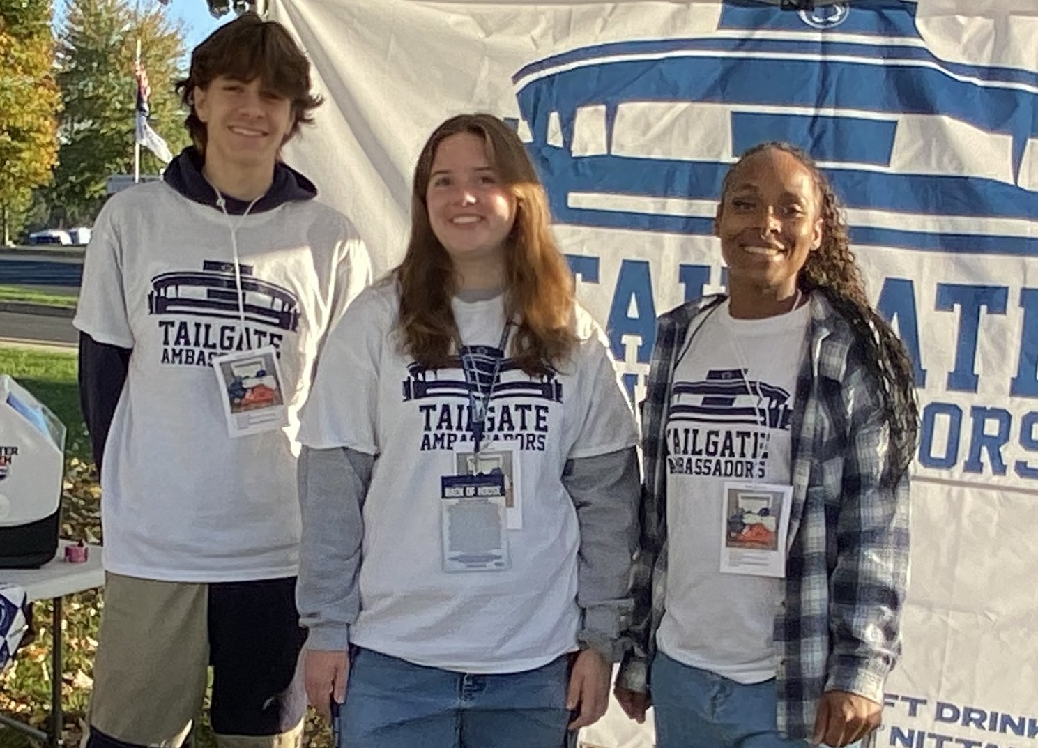 3 students stand in front of banner