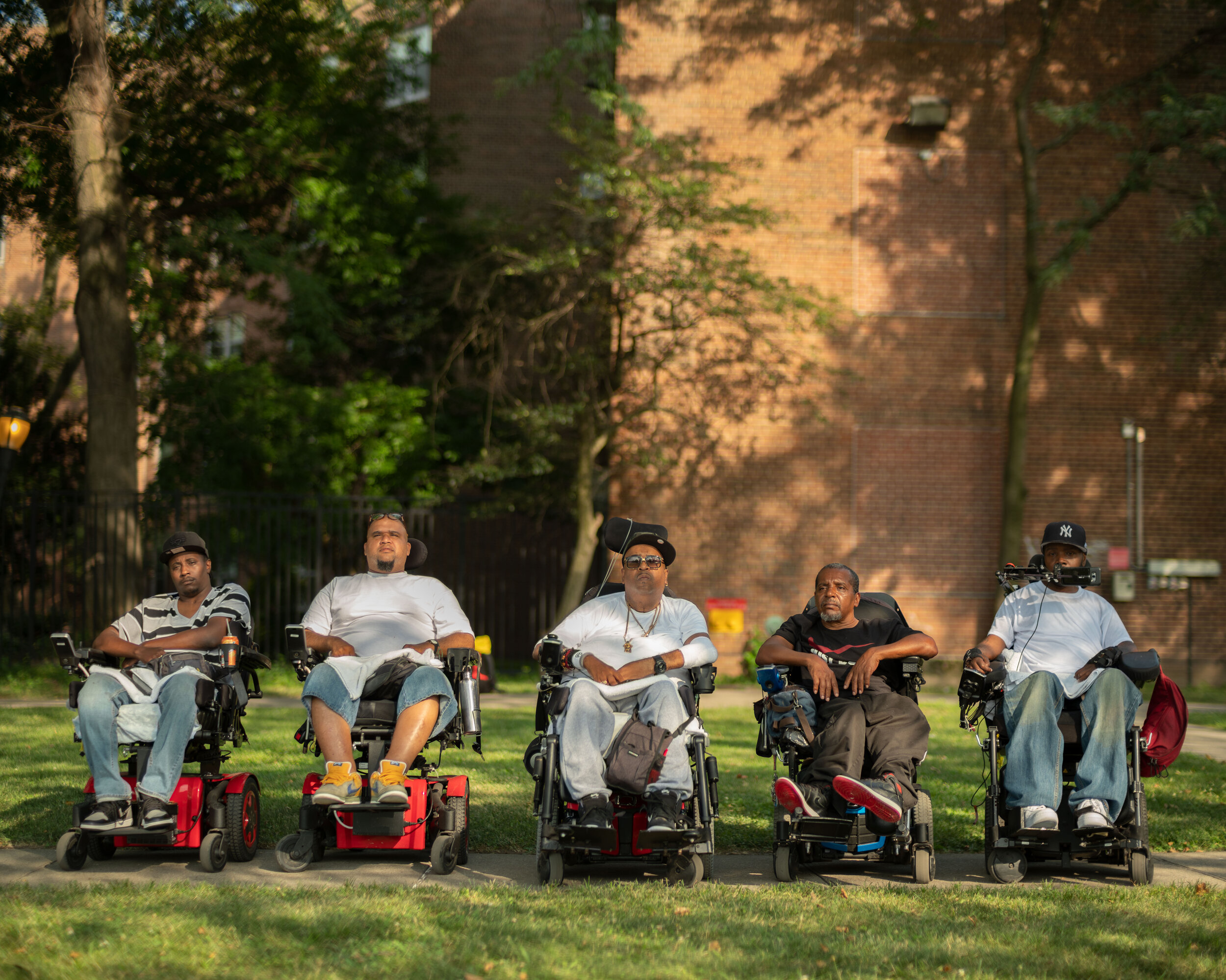 Five men in motorized wheelchairs