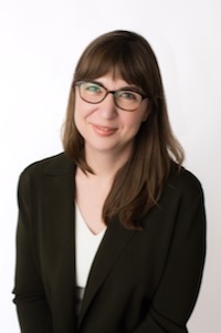 Photo of Sarah Dimick wearing a black blazer and white blouse as well as a pair of glasses